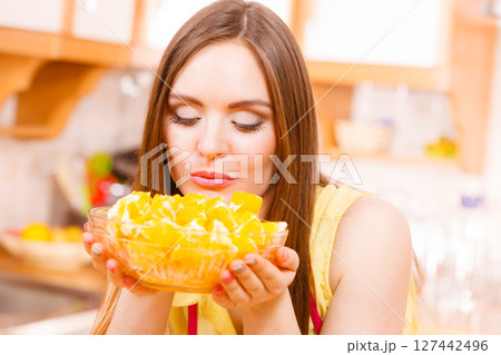 Woman holds bowl full of sliced orange fruits Woman holds bowl full of sliced orange fruits 127442496