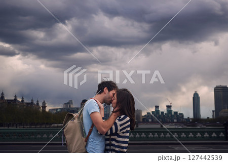 Love, couple and kiss on city bridge or outdoors in town on vacation, trip or holiday, Cloudy day, romance and affection of man and woman kissing in street, bonding and enjoying quality time together Love, couple and kiss on city bridge or outdoors in town on vacation, trip or holiday, Cloudy day, romance and affection of man and woman kissing in street, bonding and enjoying quality time together 127442539