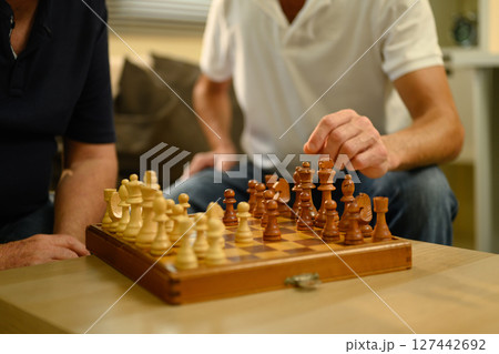 Mature father and son sit on a couch, focused on a strategic game of chess. Father day concept Mature father and son sit on a couch, focused on a strategic game of chess. Father day concept 127442692