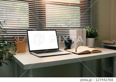 Modern home office workspace with a blank laptop screen, open notebook, and coffee mug Modern home office workspace with a blank laptop screen, open notebook, and coffee mug 127442768