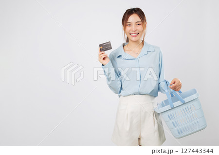 Shopping smile woman Excited holding basket and credit card, excited for more shopping at supermarket with finance goals and secure money spending plan. isolated studio white background Shopping smile woman Excited holding basket and credit card, excited for more shopping at supermarket with finance goals and secure money spending plan. isolated studio white background 127443344