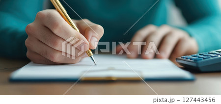 Writing in budget planner with pen, focused on financial planning 127443456