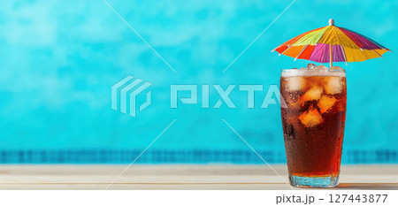 sparkling soda drink with ice and colorful umbrella, refreshing and vibrant. Perfect for summer enjoyment by poolside 127443877