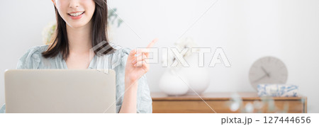 自宅の部屋でパソコンを使う若いかわいいカジュアルな服の女性カメラ目線　ポイントやオススメ 127444656