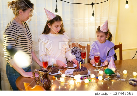 Celebration with family and friends during a joyful birthday gathering featuring decorated cake and sparkling drinks in a warm, cozy setting 127445565