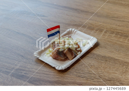 Traditional Dutch street food - saline herring with  onions and Dutch flag in a fish 127445689