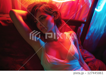 white slender young sexy woman is lying on a bed in her underwear with neon lighting 127445861