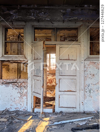 soft light shines through an abandoned doorway in decaying building at sunset. closeup. 127446629