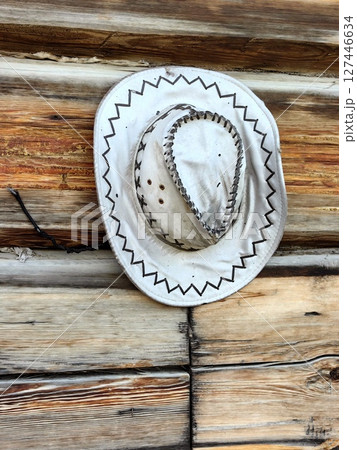 unique old cowboy hat hanging against rustic wooden wall at countryside location. closeup. unique old cowboy hat hanging against rustic wooden wall at countryside location. closeup. 127446634