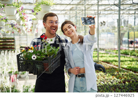 Making selfie, smiling. Florist man and woman are working together in bright greenhouse 127446925