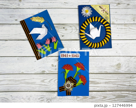 Three handmade cards for Victory Day with paper crafts. Featuring red carnations, origami dove and crane, St. George ribbon, and date 1941-1945 in memory of WWII Three handmade cards for Victory Day with paper crafts. Featuring red carnations, origami dove and crane, St. George ribbon, and date 1941-1945 in memory of WWII 127446994