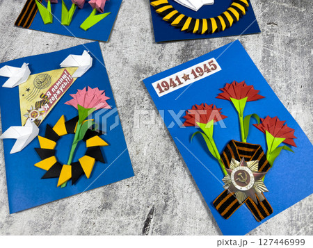 Victory Day cards with iconic Soviet symbols: red carnations, the Saint George ribbon, and the 1941-1945 war date. Handmade tribute to remembrance and peace 127446999