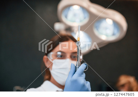 Woman holding syringe. In the stomatological cabinet 127447605