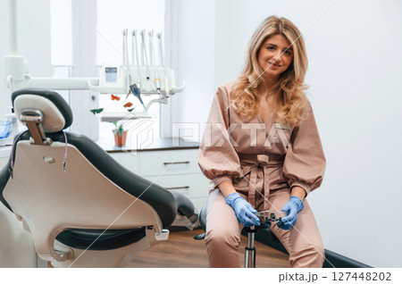 Beautiful woman doctor is sitting. In the stomatological cabinet 127448202