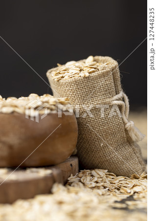 bag with oatmeal flakes, scattered dry cereal flakes from oats, flattened, steamed and dried, side view 127448235
