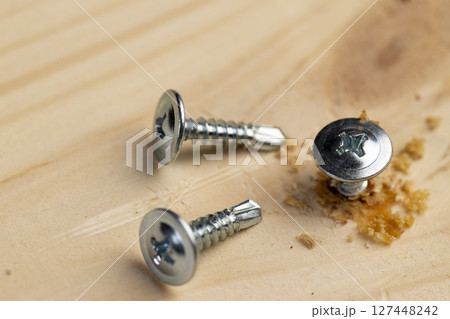 silver self-tapping screws for wood on the board, closeup silver self-tapping screws for wood on the board, closeup 127448242
