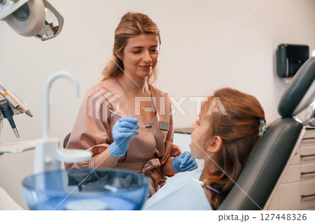 Female doctor is working with little girl. In the stomatological cabinet Female doctor is working with little girl. In the stomatological cabinet 127448326