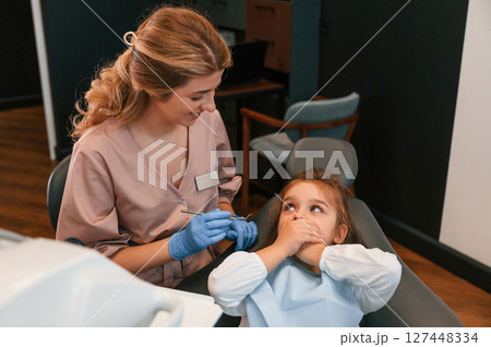 Little girl is sitting with the female doctor. In the stomatological cabinet 127448334