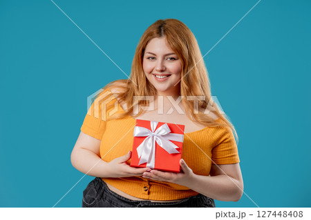 Happy body positive woman with Gift Box On Blue Background. Full figured lady Happy body positive woman with Gift Box On Blue Background. Full figured lady 127448408