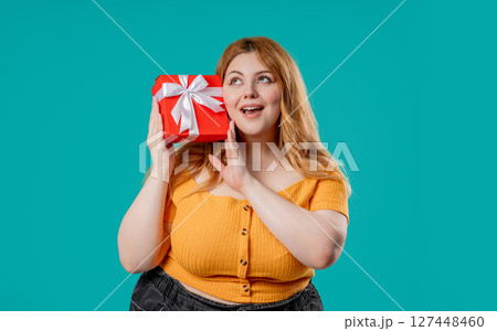 Happy body positive woman with Gift Box On Blue Background. Full figured lady  127448460