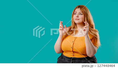 Curvy woman praying with crossed fingers, blue background. Lady begs someone, satisfy desires, help Curvy woman praying with crossed fingers, blue background. Lady begs someone, satisfy desires, help 127448464