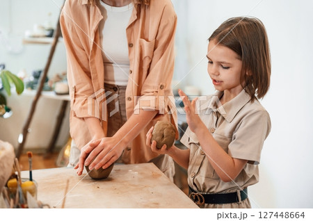 Creating the shape by using clay. Mother with little girl doing pottery at home Creating the shape by using clay. Mother with little girl doing pottery at home 127448664