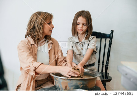Creating the pot. Mother with little girl doing pottery at home 127448683