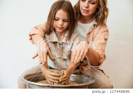 Making the pot out of clay. Mother with little girl doing pottery at home 127448690