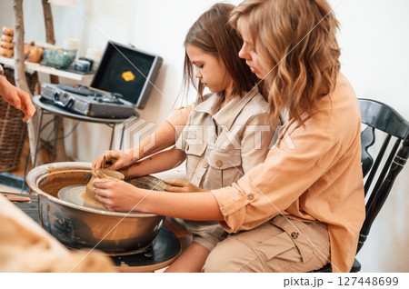 Pottery wheel. Mother with little girl making ceramic pot in the workshop Pottery wheel. Mother with little girl making ceramic pot in the workshop 127448699