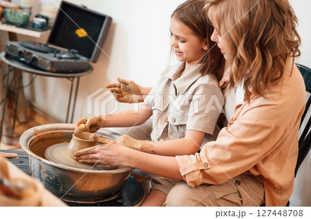 Sitting, creating the shape. Mother with little girl doing pottery at home Sitting, creating the shape. Mother with little girl doing pottery at home 127448708