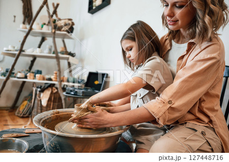 In the workshop. Mother with little girl making ceramic pot 127448716