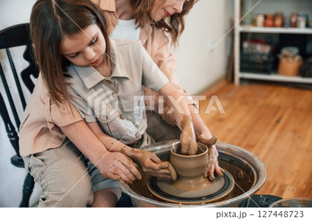 Using clay to create the pot. Mother with little girl learning pottery in the workshop Using clay to create the pot. Mother with little girl learning pottery in the workshop 127448723