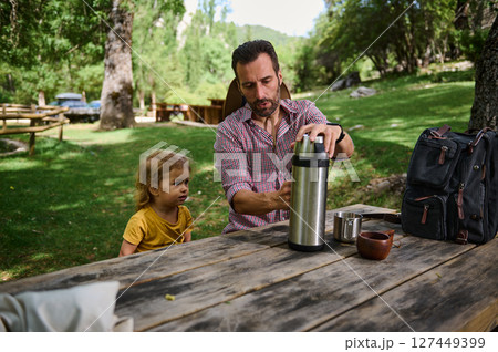 Father with Child Relaxing Outdoors in Scenic Nature at Picnic Scene 127449399