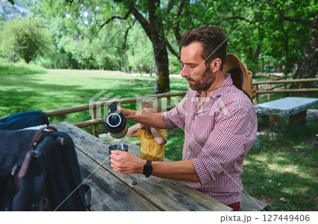 Man Enjoying an Outdoor Picnic in Nature with Family at a Scenic Park Man Enjoying an Outdoor Picnic in Nature with Family at a Scenic Park 127449406