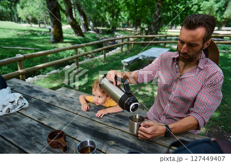 Father and Child Enjoying a Relaxing Outdoor Picnic Amidst Nature 127449407