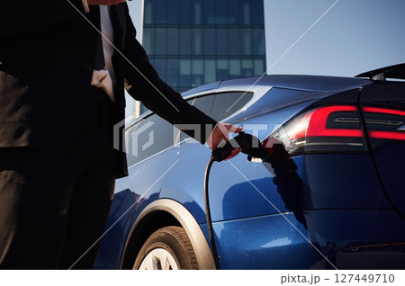 Charging process. Businessman is standing near his electric car outdoors 127449710