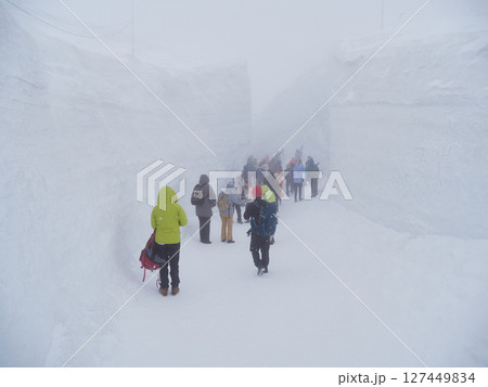 吹雪の中で観光名所立山黒部アルペンルートの室堂にいる観光客の姿 127449834