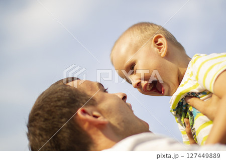 Happy father throws up his little son against the background of the sky. Happy father throws up his little son against the background of the sky. 127449889