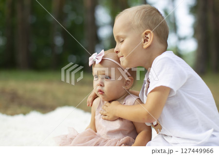 The older brother hugs his little sister for a walk in the park. The older brother hugs his little sister for a walk in the park. 127449966