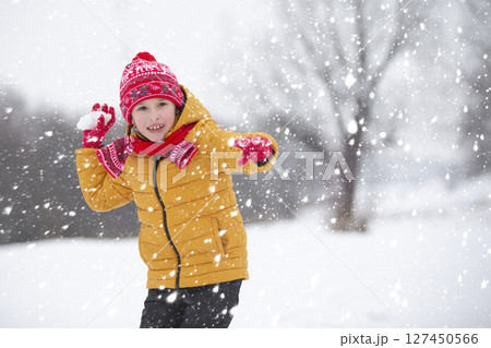 Child in winter. The boy is playing snowballs in the street. Child in winter. The boy is playing snowballs in the street. 127450566