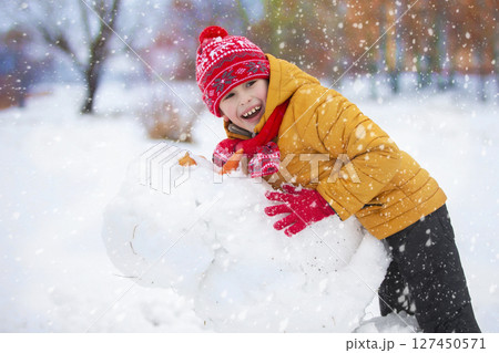 Child in winter. A happy boy in bright clothes plays in the snow. Child in winter. A happy boy in bright clothes plays in the snow. 127450571