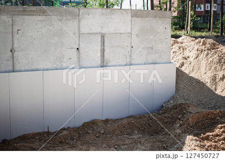 Construction site showing newly installed concrete wall and ground preparation for building foundations 127450727