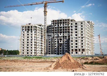 Construction site of residential buildings with cranes under a clear sky in a developing area Construction site of residential buildings with cranes under a clear sky in a developing area 127450742