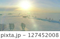 Aerial view of cold winter landscape arctic field, trees covered with frost snow, ice river and sun rays over horizon. Extreme low temperature weather. 127452008