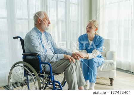 Help support retirement healthcare. Nurse helping old man in wheelchair. Patient and woman in nursing home for medical caregiver. Nurse taking care of paralyzed man in chair for people with disability Help support retirement healthcare. Nurse helping old man in wheelchair. Patient and woman in nursing home for medical caregiver. Nurse taking care of paralyzed man in chair for people with disability 127452404