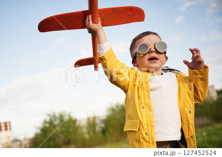Red colored toy plane. Little boy is playing on the summer field Red colored toy plane. Little boy is playing on the summer field 127452524