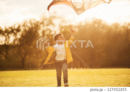 Amazing sunlight. Little boy is playing with a kite on the field at summer time Amazing sunlight. Little boy is playing with a kite on the field at summer time 127452855
