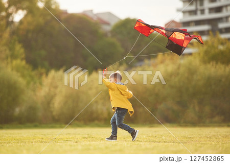 Running with kite. Little boy is playing on the field at summer time 127452865