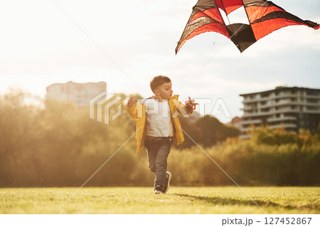 On green meadow. Little boy is playing with a kite On green meadow. Little boy is playing with a kite 127452867