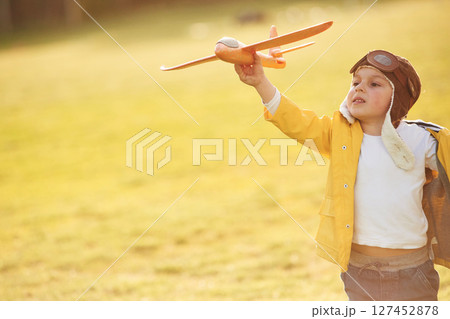 Retro style aviator glasses. Little boy is playing with toy plane on the summer field 127452878